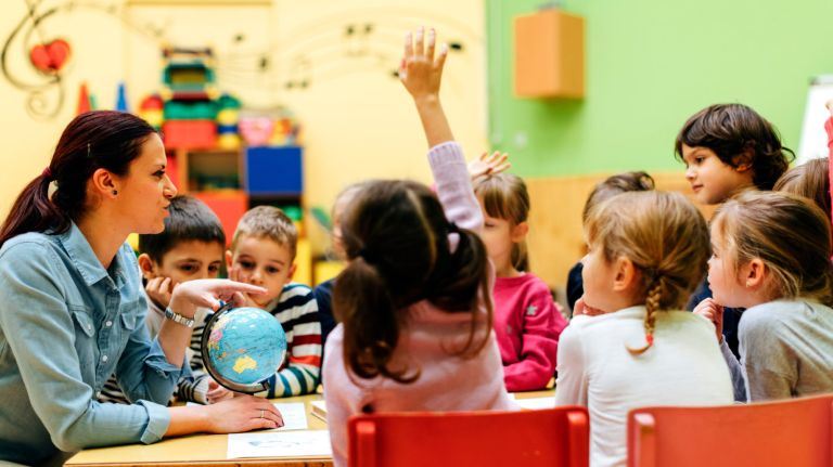 Pre-school teacher speaking with children at a table